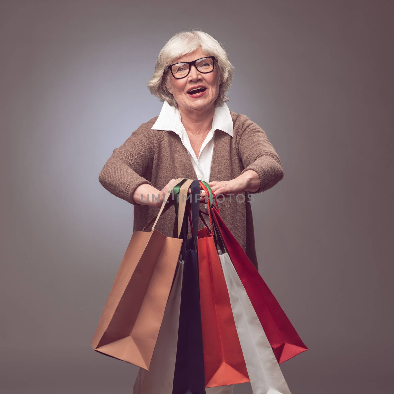 Shopper senior woman holding shopping bags possing happy smiling and excited