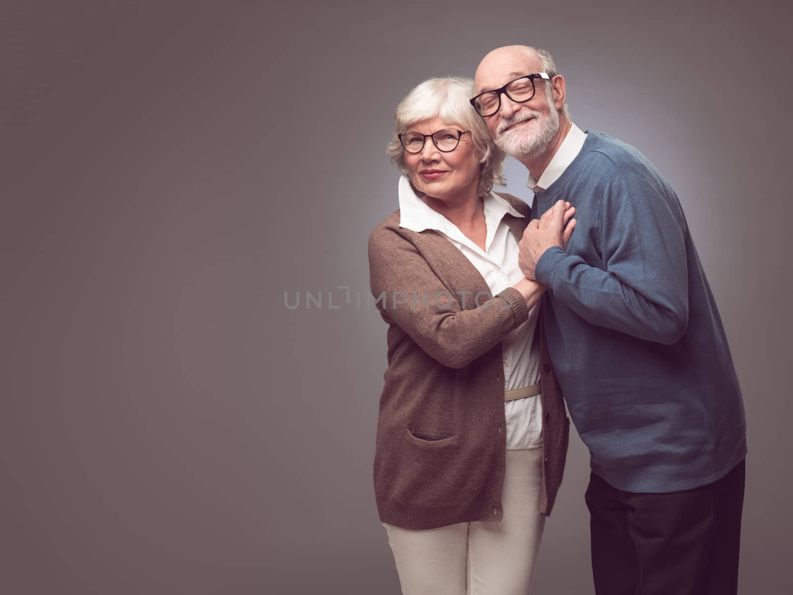 Portrait of a sweet senior couple embracing , casual clothes, gray background
