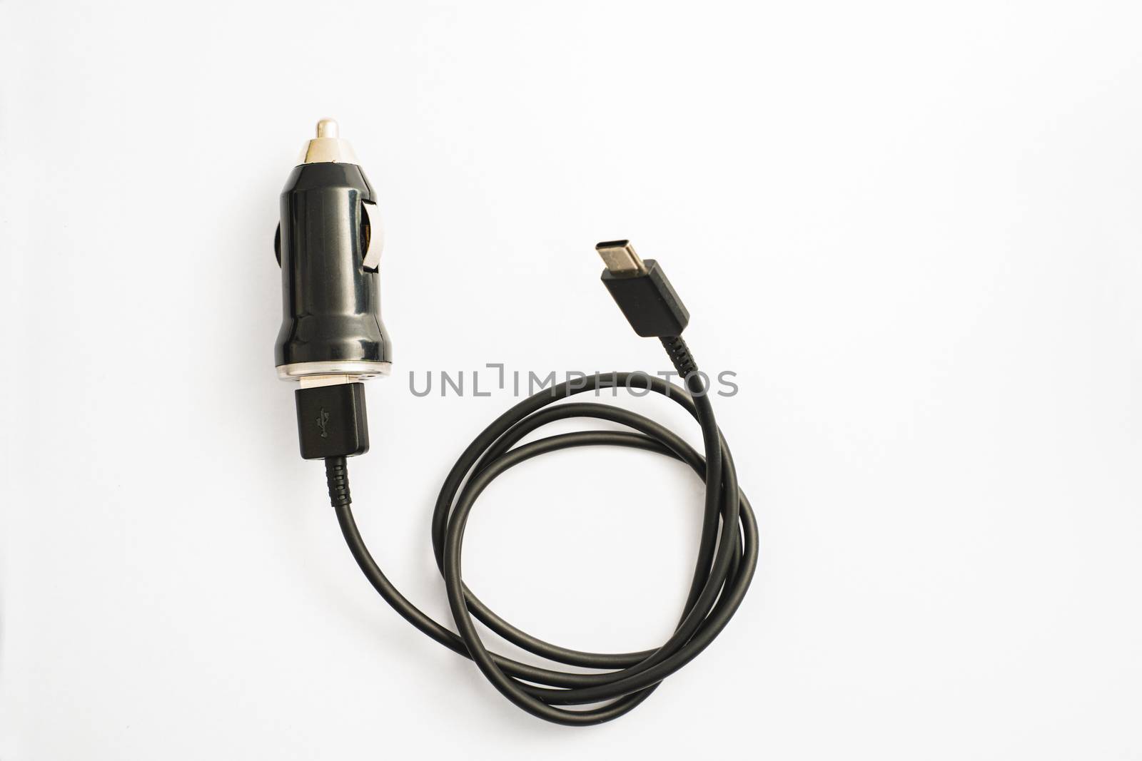 The black car charger with USB output connection cable. A photo taken on a black car charger with USB output connection cable against a white backdrop