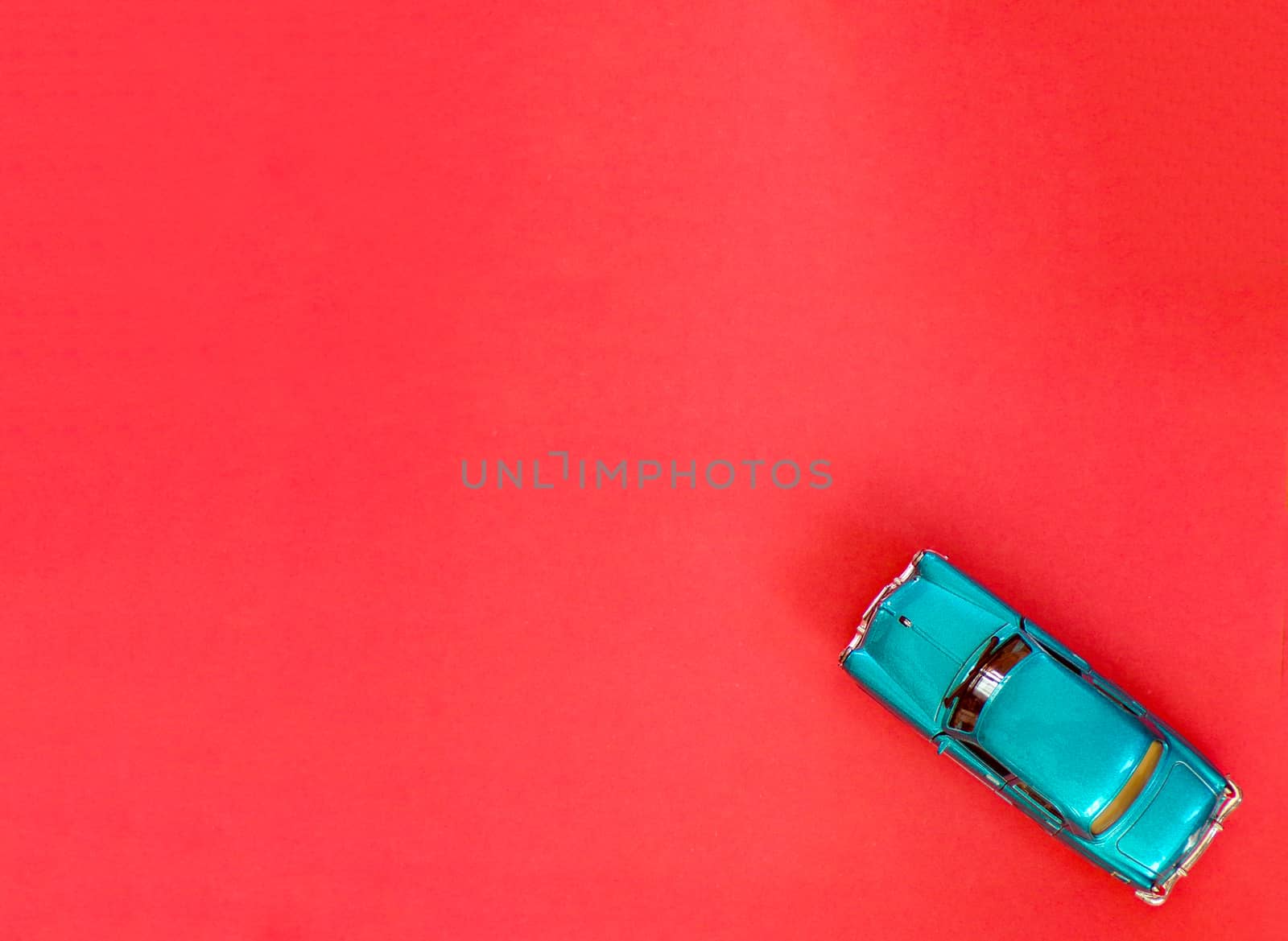Toy car on a red background with copying space. The car model is made of blue metal.