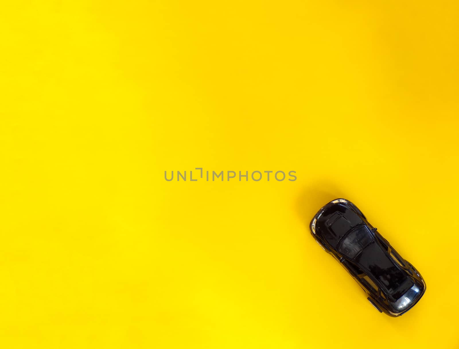 Children's toy car on a yellow background with copying space.