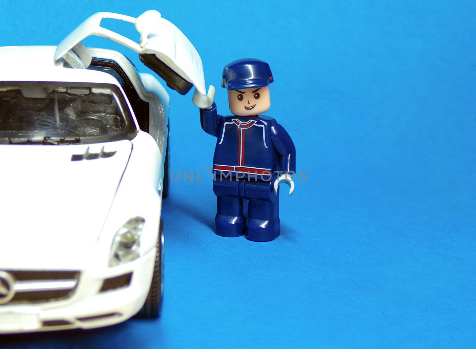 Man and car in the form of children's toys. Buying a new car. Successful and rich man. The driver of the car. A car and a human figure on a blue background.Happy little man.