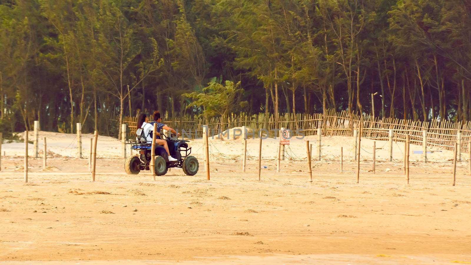 Honeymoon couple riding Motorized tricycle (three wheeled Trike motorcycle) in the coastal road of sand sea beach in summer sunset. Travel Tourism Holiday vacation background concept. by sudiptabhowmick