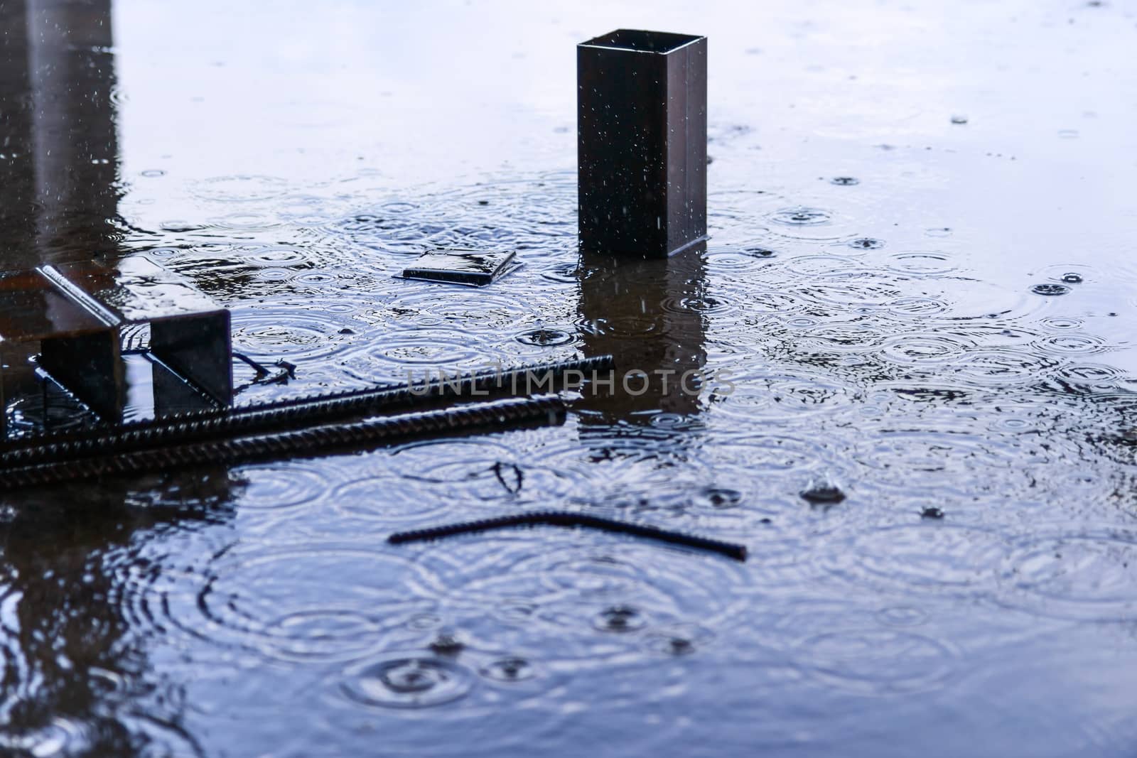 Rain drops and water on concrete with sky reflection in water