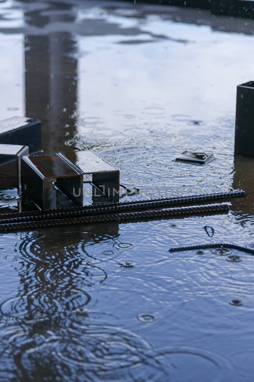 A parts of big square pipes and fixtures under summer rain on construction.