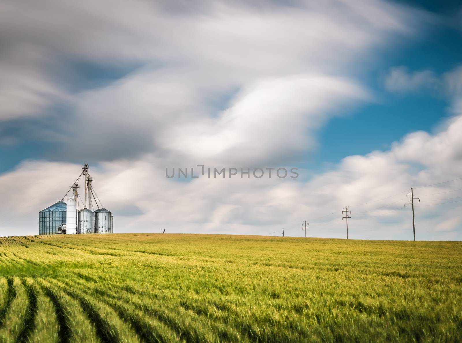 Grain Elevator on Hill with Blurry Clouds.