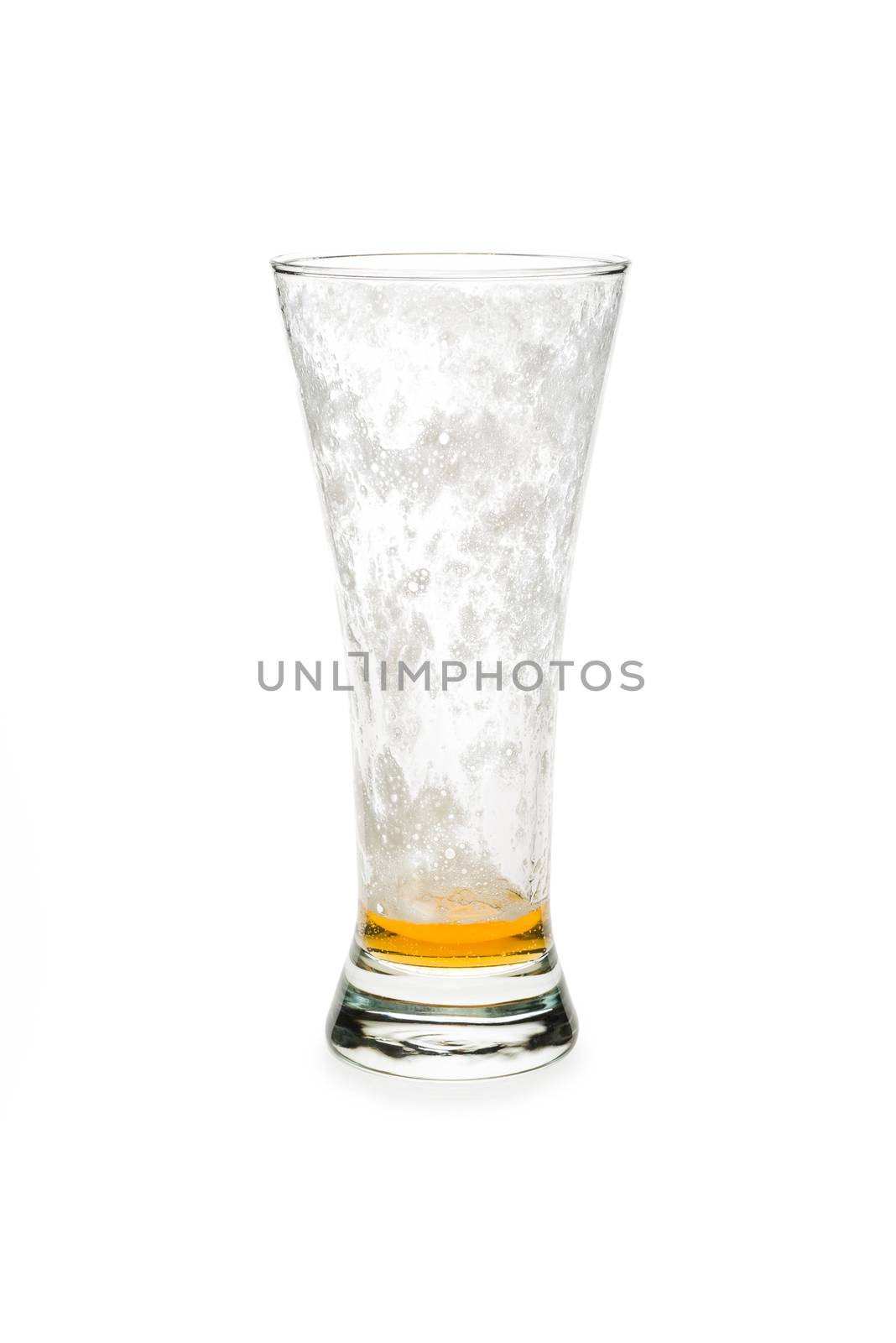 Almost empty pilsner beer glass isolated against white background.