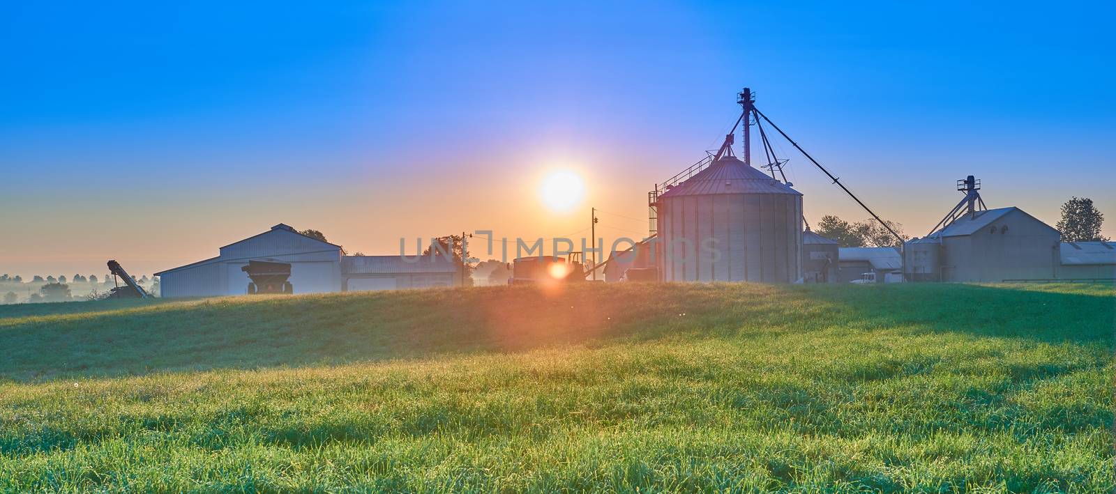 Sunrise Over Farm with Silo and blue Sky. by patrickstock
