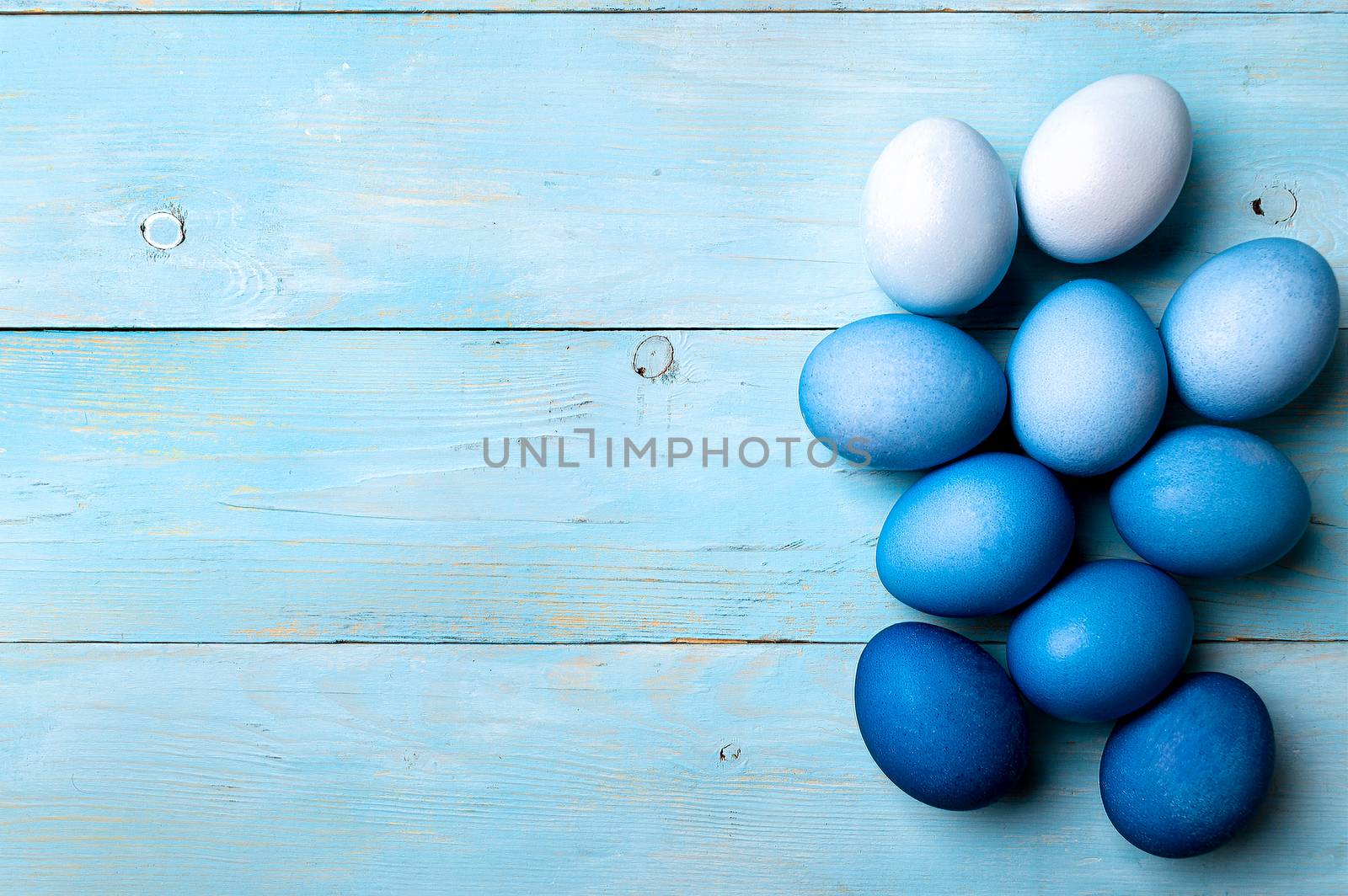 Easter concept. Ombre eggs in blue colors on blue wooden background with copy space for text. Top down view or flat lay. Classic blue colors in Easter 2020