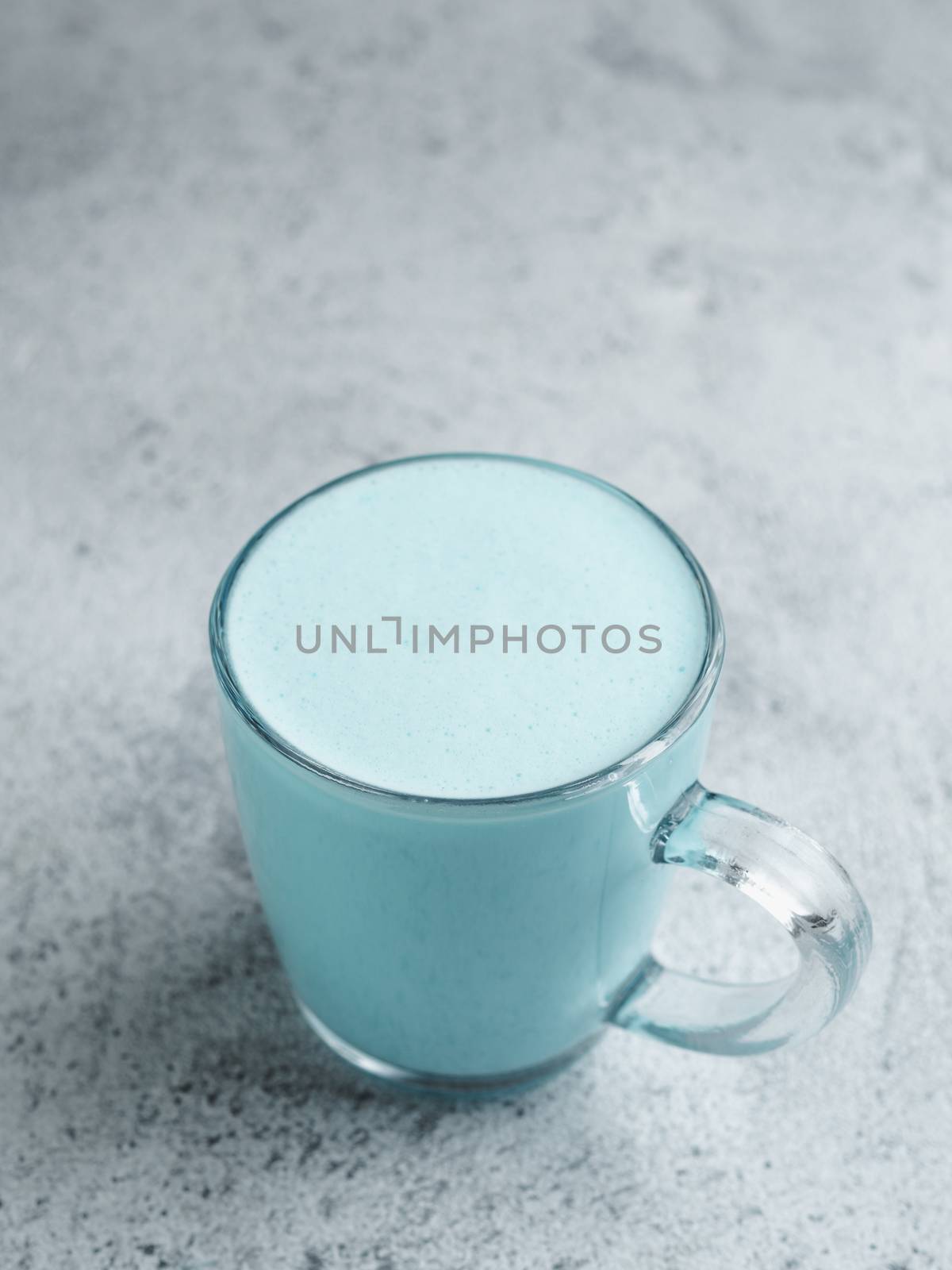 Trendy drink: Blue latte. Top view of hot butterfly pea latte or blue spirulina latte on gray cement textured background. Copy space for text.