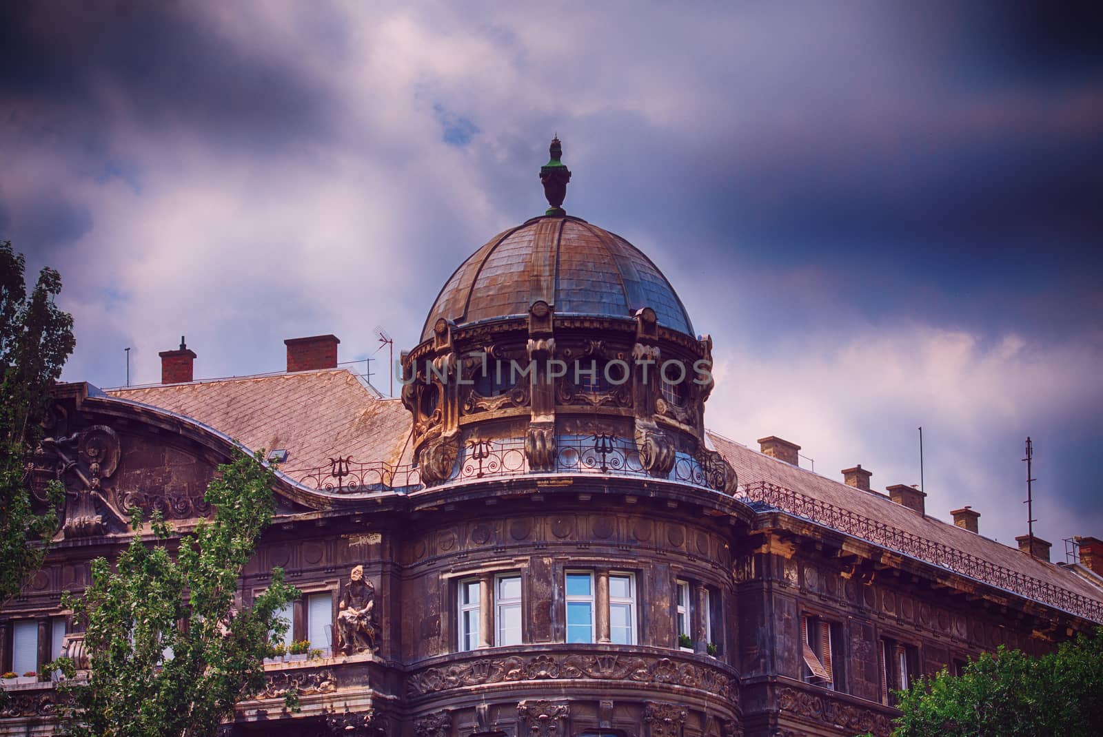 Beautiful domed old building in Budapest with dark blue stormy clouds in the background. The calm before the storm in Budapest.