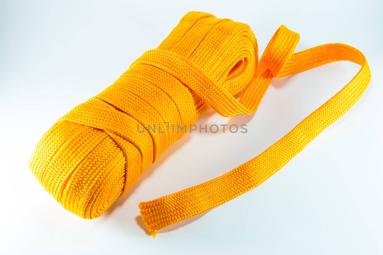 Orange rope rolls flat on white background.
