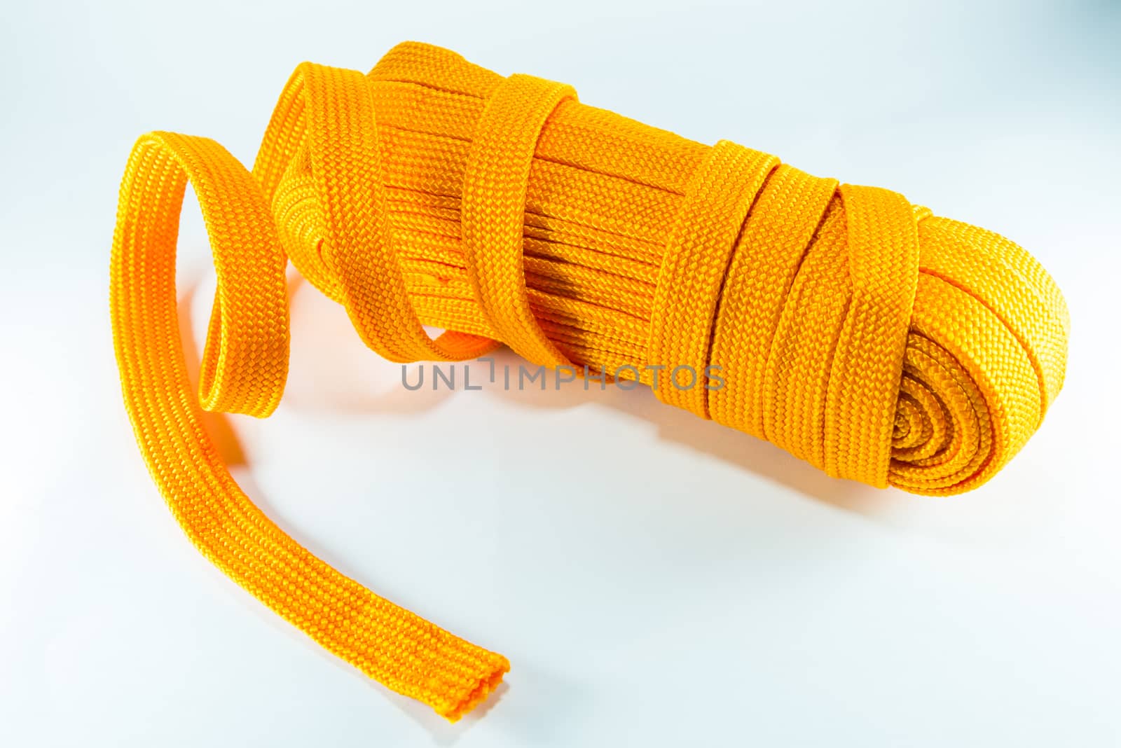 Orange rope rolls flat on white background.