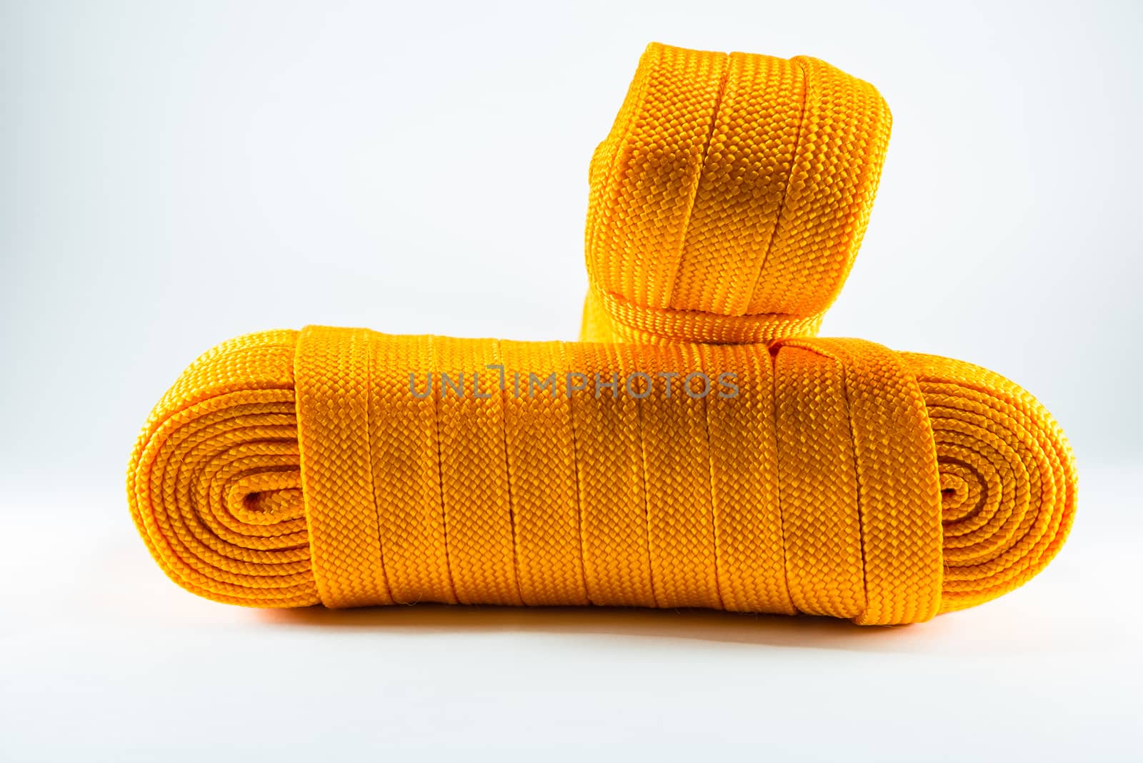 Orange rope rolls flat on white background.