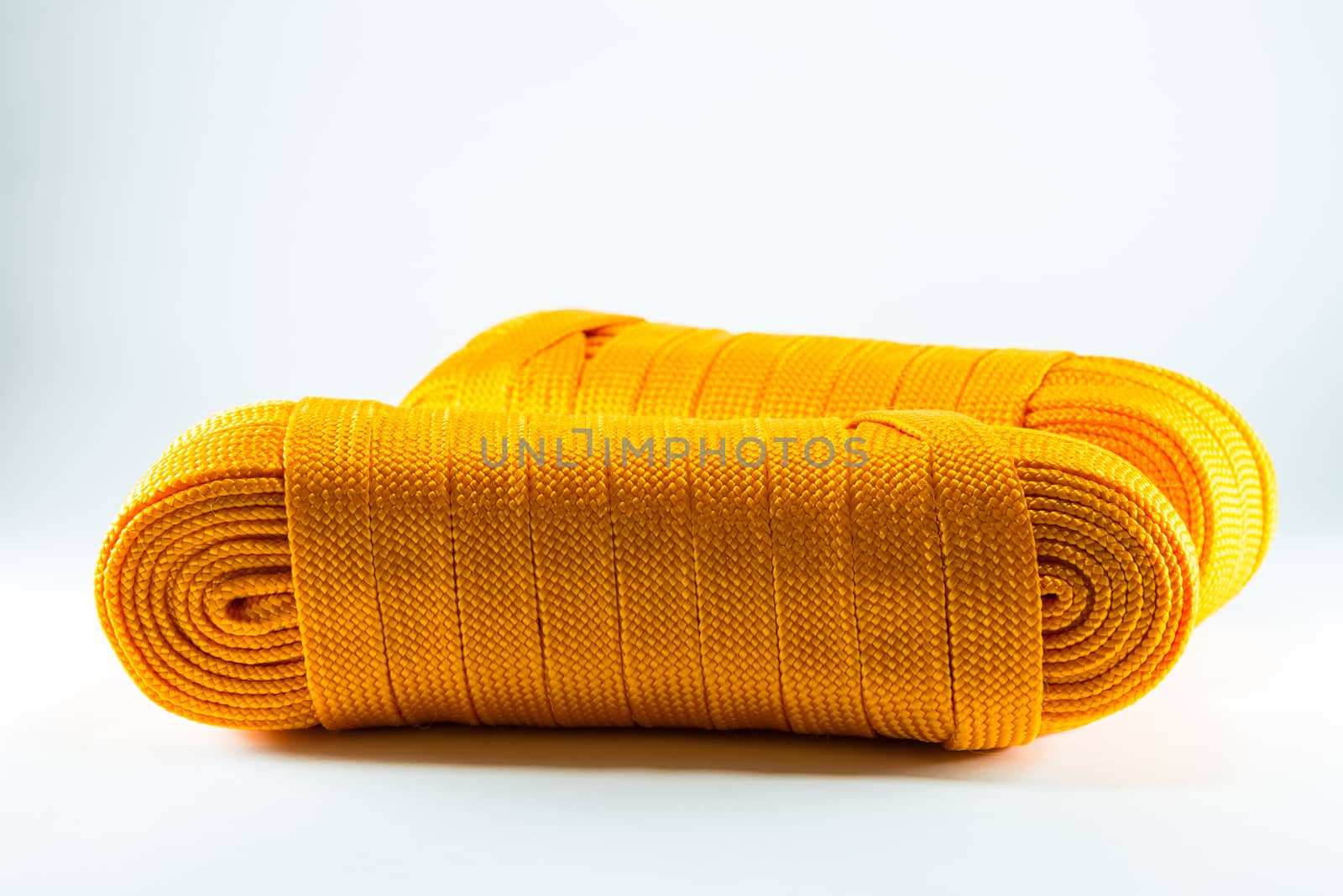 Orange rope rolls flat on white background.