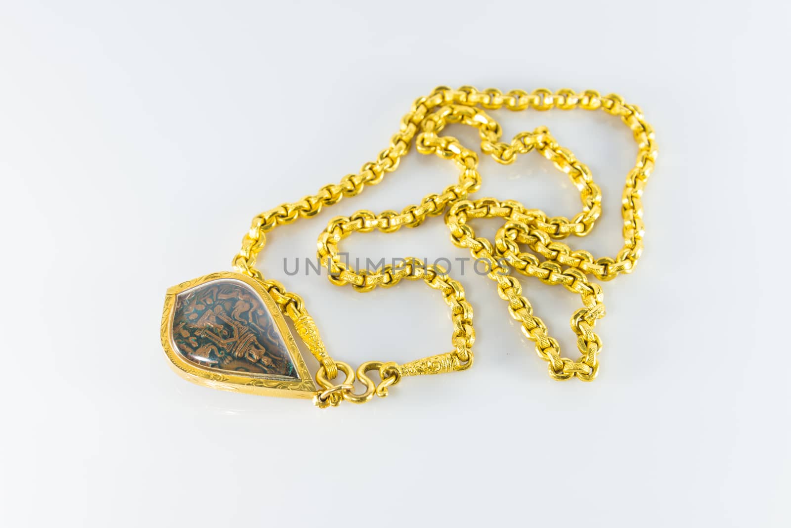 Gold necklaces and amulets on white background.