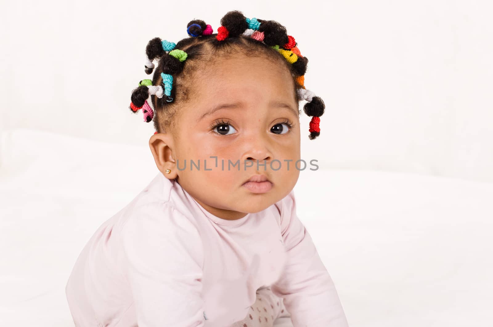 Portrait of cute baby girl looking at camera on a white background.