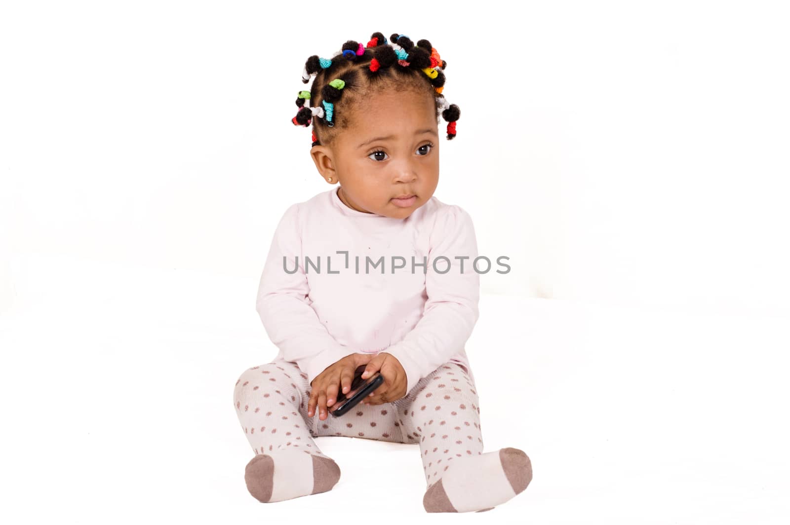 Pretty baby sitting and playing with a cell phone on white background