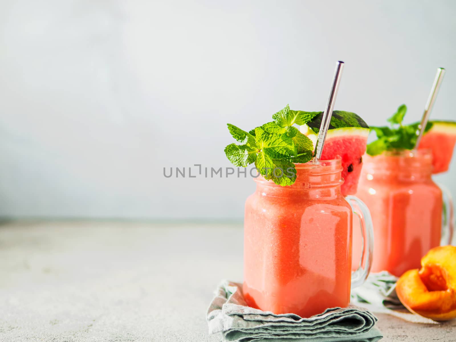 Freshly Blended Watermelon and Peach Smoothies in mason jar and metal straw. Copy space for text or design.