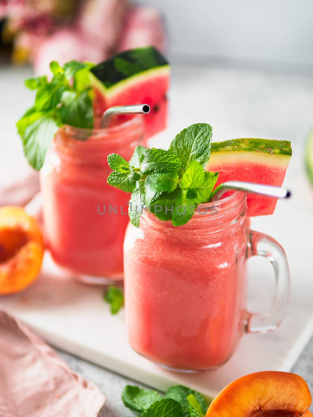Freshly Blended Watermelon and Peach Smoothies in mason jar and metal straw. Copy space for text or design. Vertical.