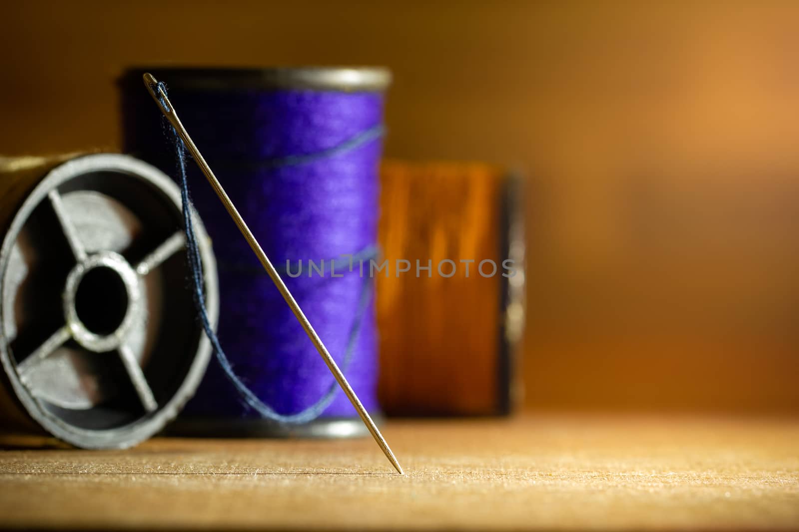 Needle and threads on wooden table. Closeup and copy space for text. Concept of tailor or Designer.