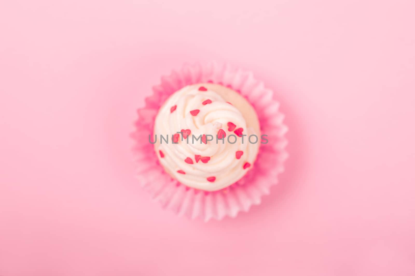 Valentine day love cupcake decorated with cream and hearts on pink background with copy space for text top view