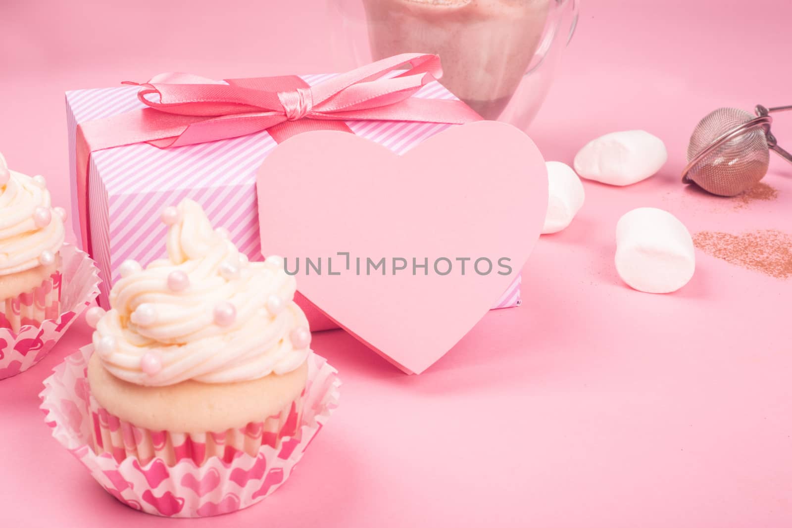 Valentine day love cupcake decorated with cream gift and hearts on pink background with copy space for text