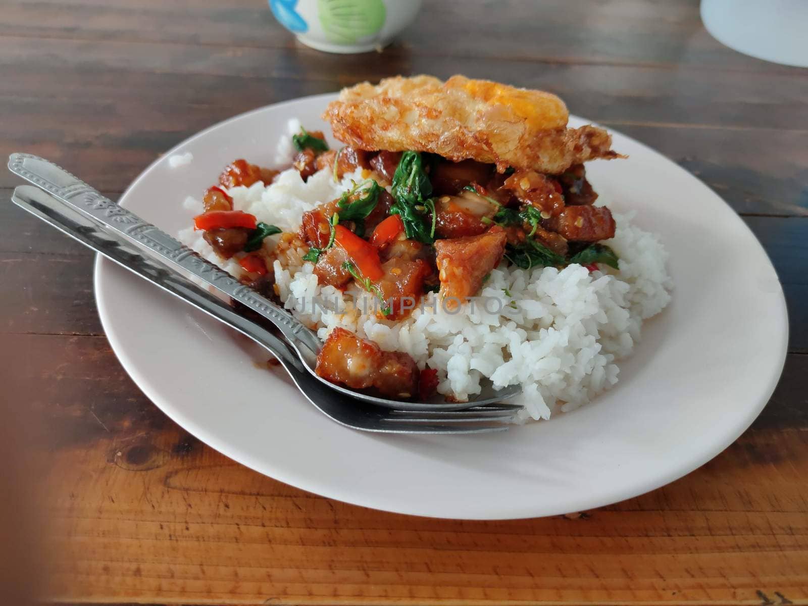 crispy pork belly with Thai basil and fried egg on rice by peerapixs