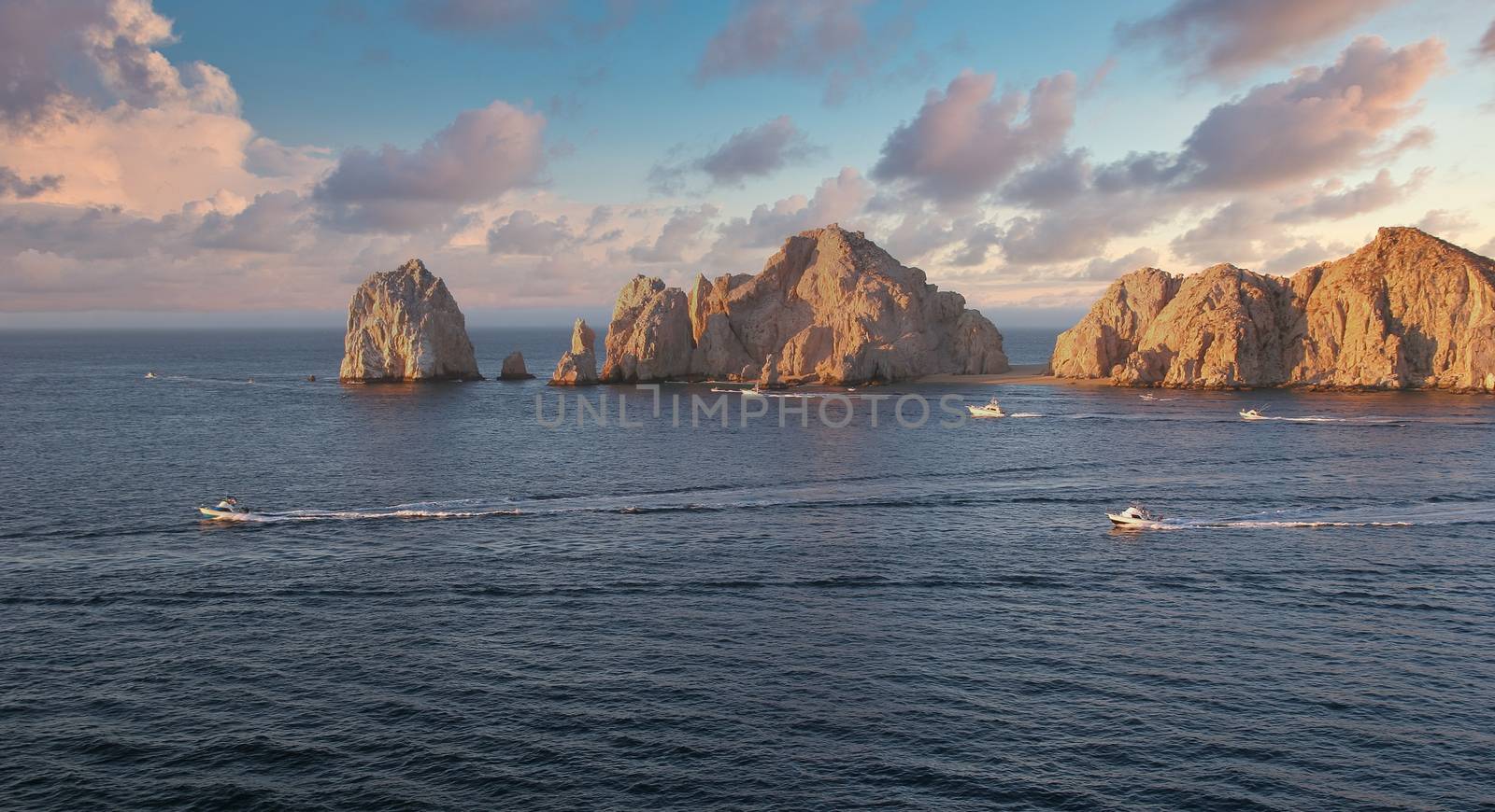 The rocks at Cabo San Lucas at Dawn with fishing boats heading out for the day