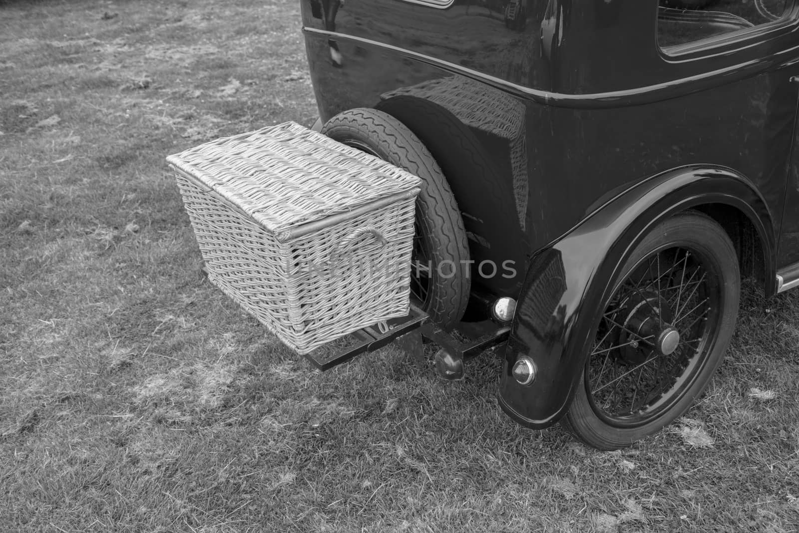 old luxury car with large mudguards and a basket on the back in black and white