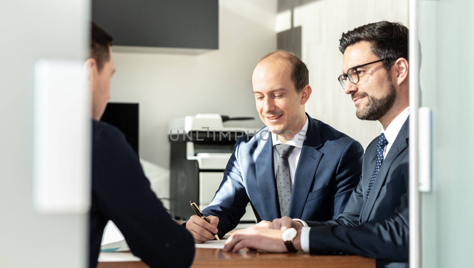 Group of confident successful business people reviewing and signing a contract to seal the deal at business meeting in modern corporate office. by kasto