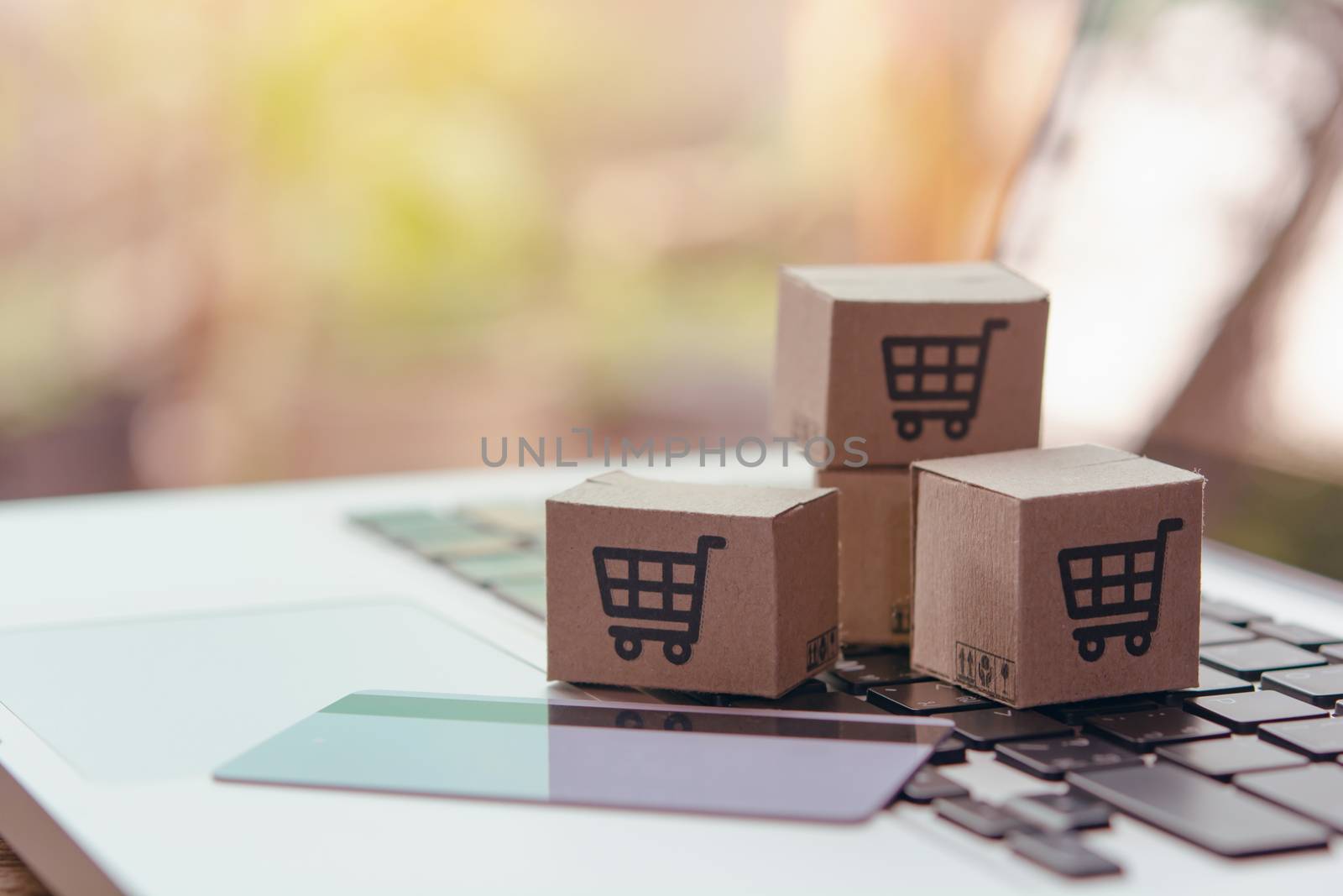 Online shopping - Paper cartons or parcel with a shopping cart logo and credit card on a laptop keyboard. Shopping service on The online web and offers home delivery.

