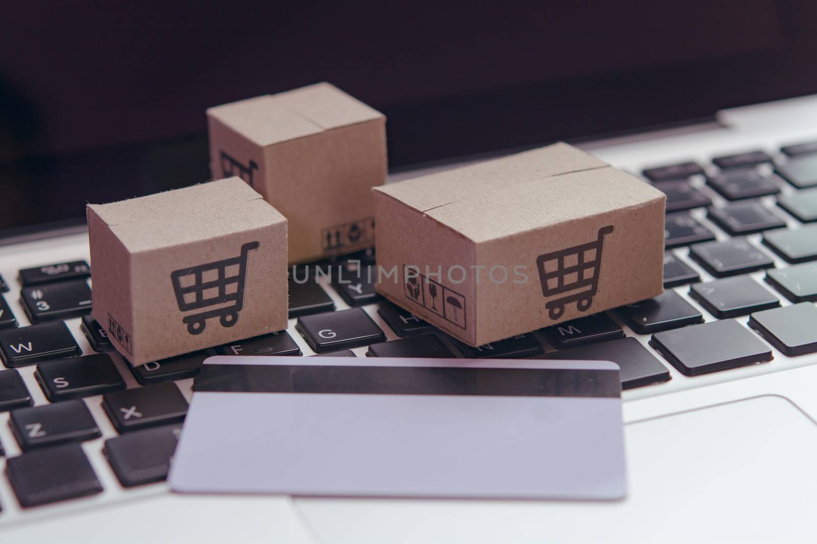 Online shopping - Paper cartons or parcel with a shopping cart logo and credit card on a laptop keyboard. Shopping service on The online web and offers home delivery.

