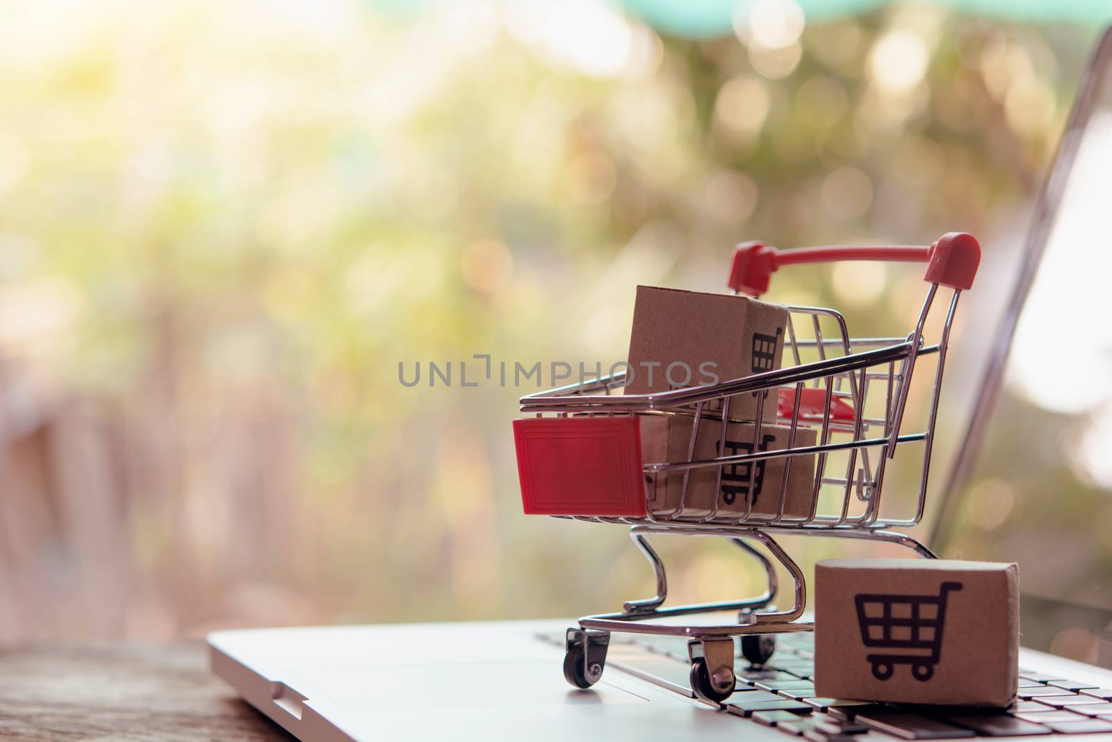 Shopping online concept - Parcel or Paper cartons with a shopping cart logo in a trolley on a laptop keyboard. Shopping service on The online web. offers home delivery.

