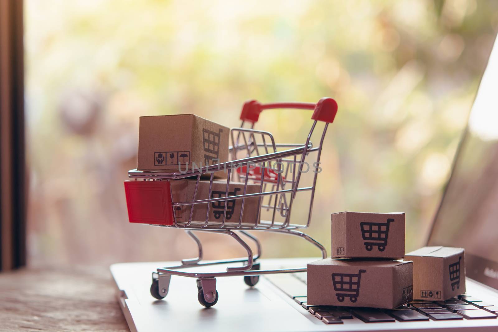 Shopping online concept - Parcel or Paper cartons with a shopping cart logo in a trolley on a laptop keyboard. Shopping service on The online web. offers home delivery.

