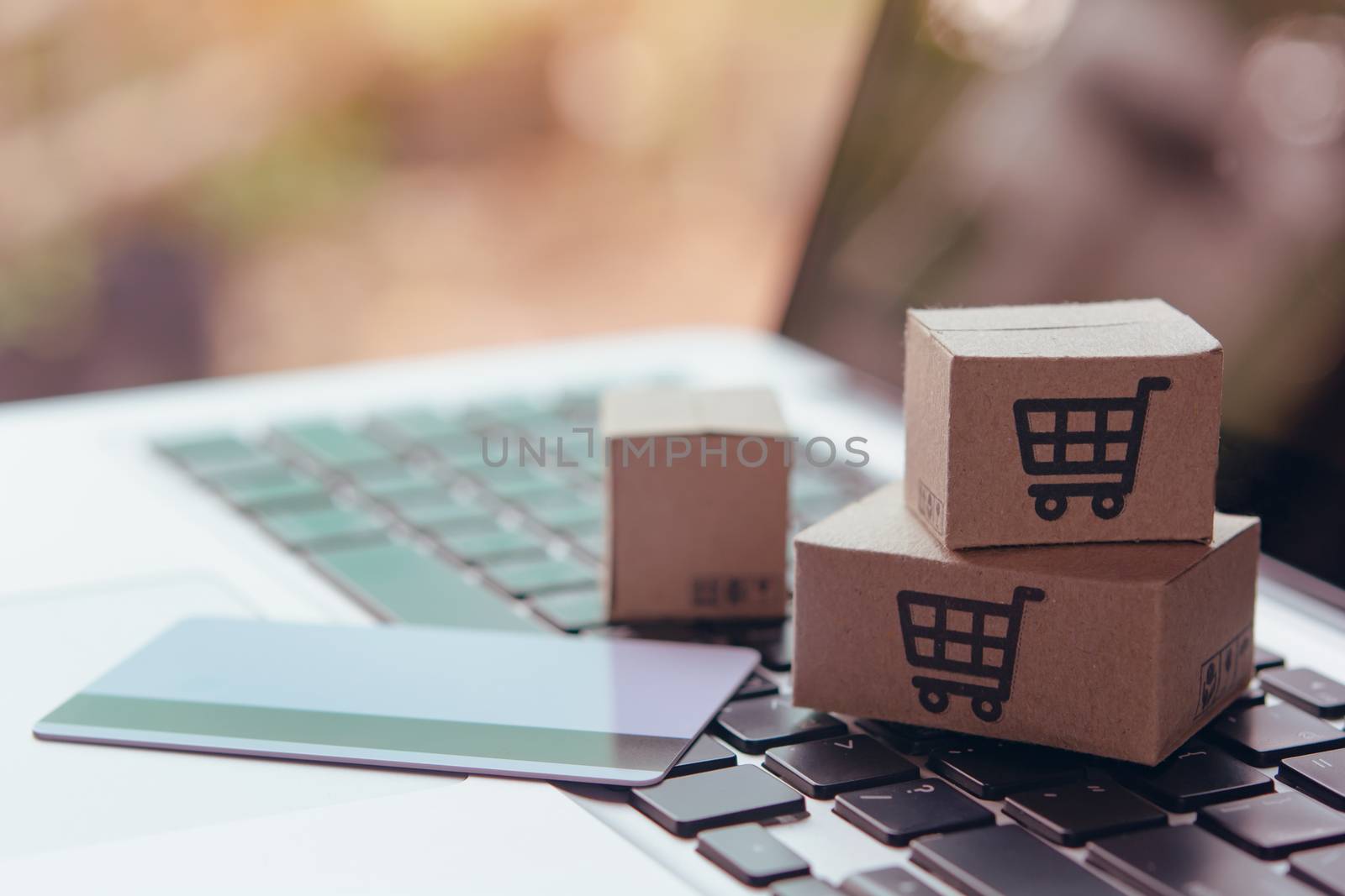 Online shopping - Paper cartons or parcel with a shopping cart logo and credit card on a laptop keyboard. Shopping service on The online web and offers home delivery.

