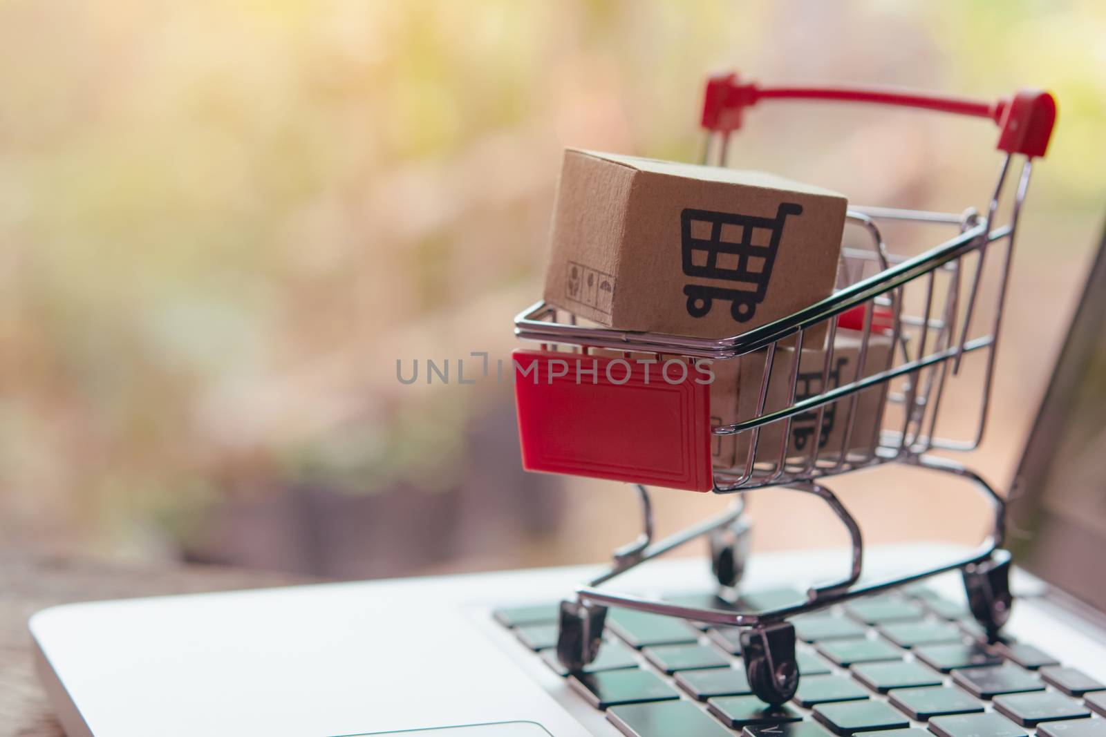 Shopping online concept - Parcel or Paper cartons with a shopping cart logo in a trolley on a laptop keyboard. Shopping service on The online web. offers home delivery.

