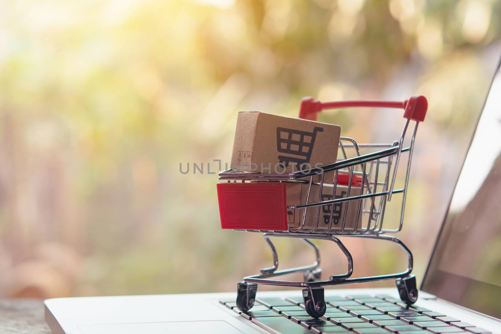 Shopping online concept - Parcel or Paper cartons with a shopping cart logo in a trolley on a laptop keyboard. Shopping service on The online web. offers home delivery.

