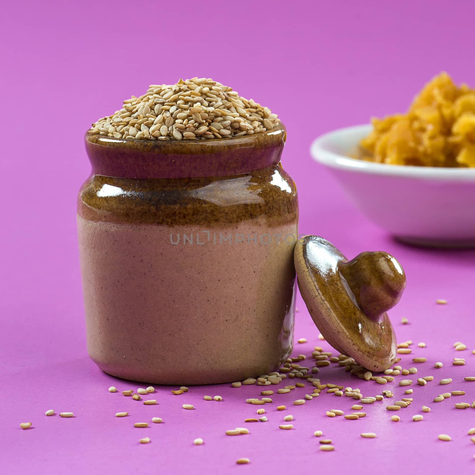 Sesame Seeds in clay pot with Jaggery in bowl on pink background