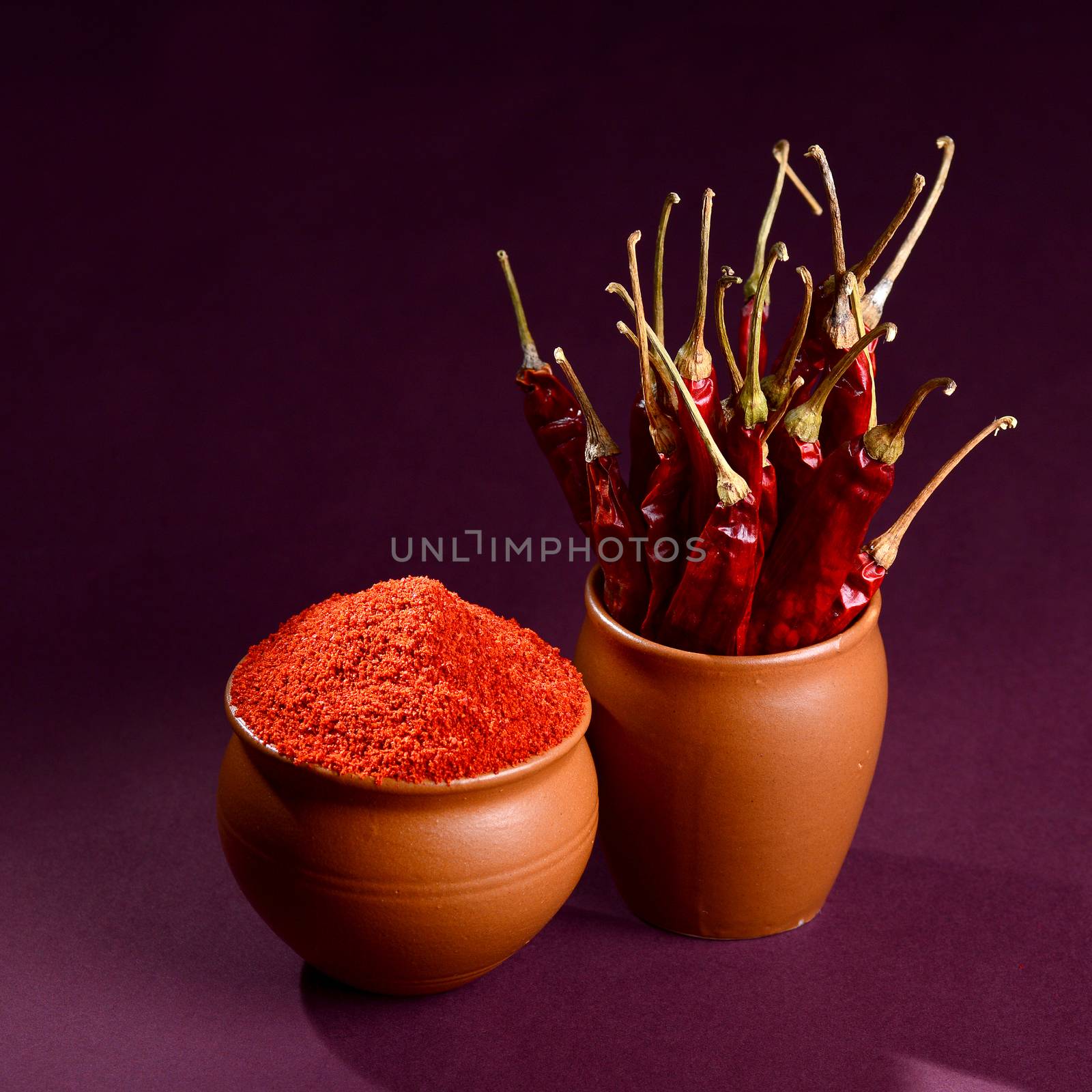 chilly powder with red chilly in clay pots, dried chillies on dark background