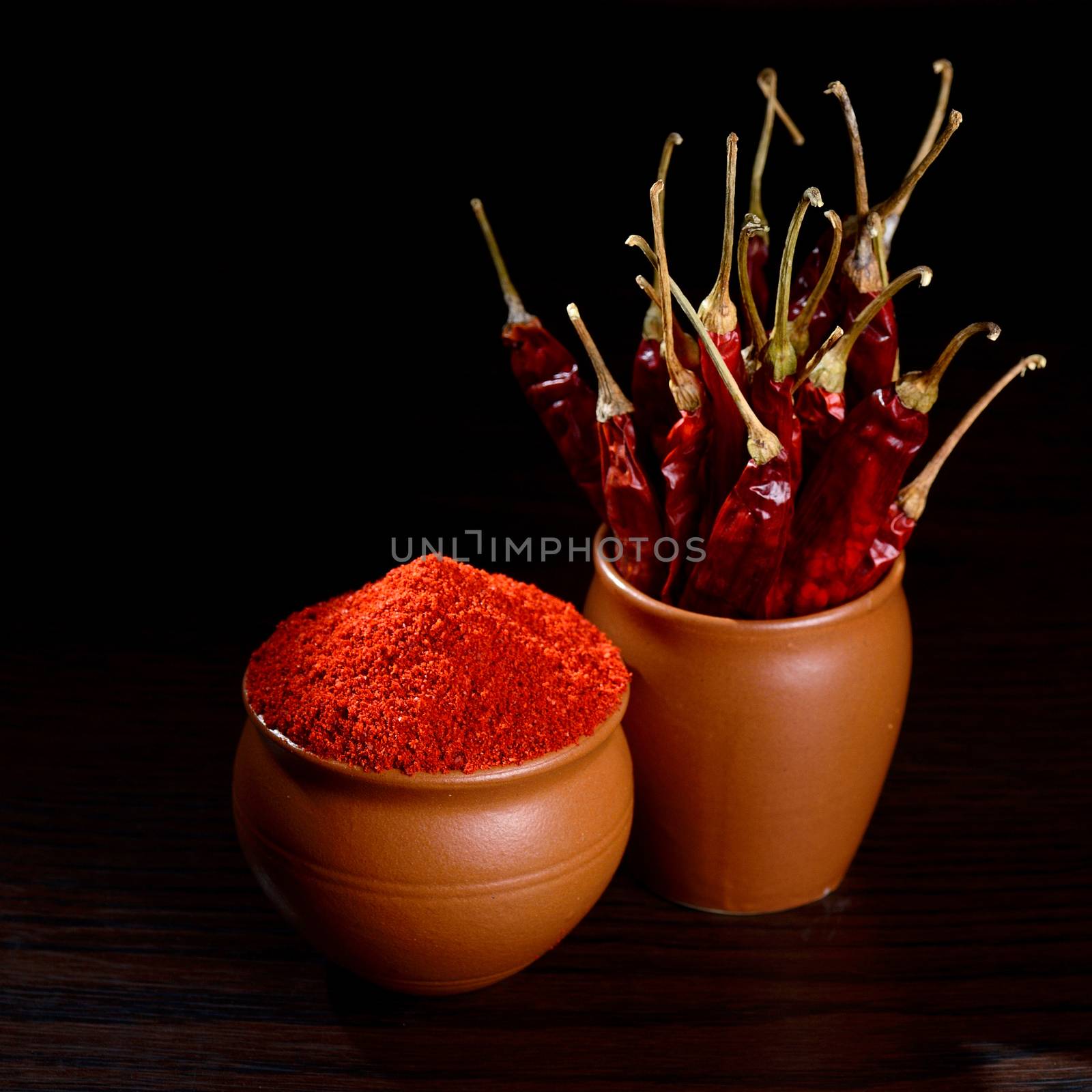 chilly powder with red chilly in clay pots, dried chillies on dark background