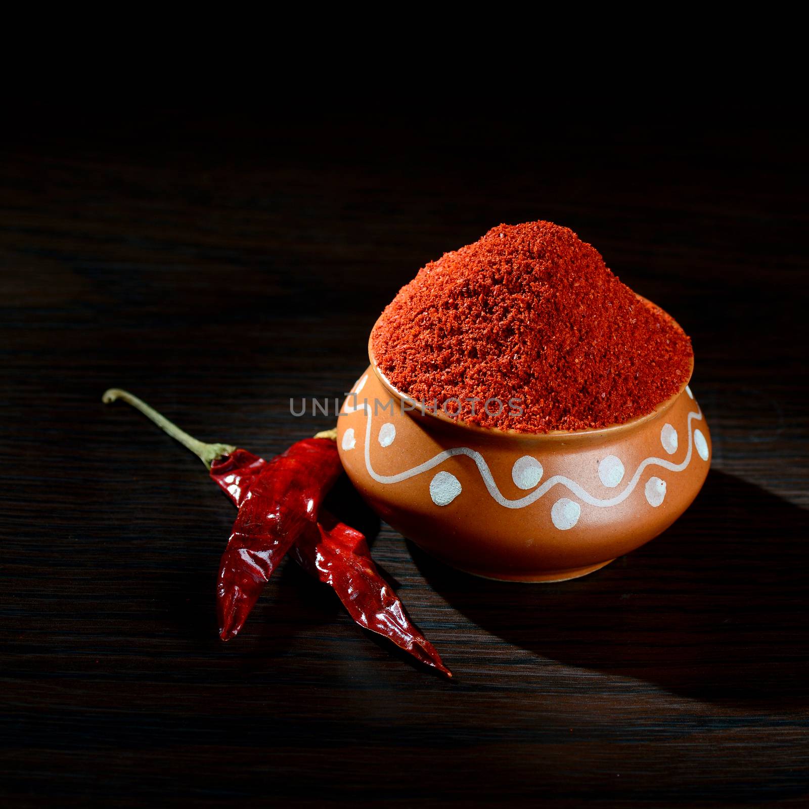 chilly powder in clay pot with red chilly, dried chillies on wooden background