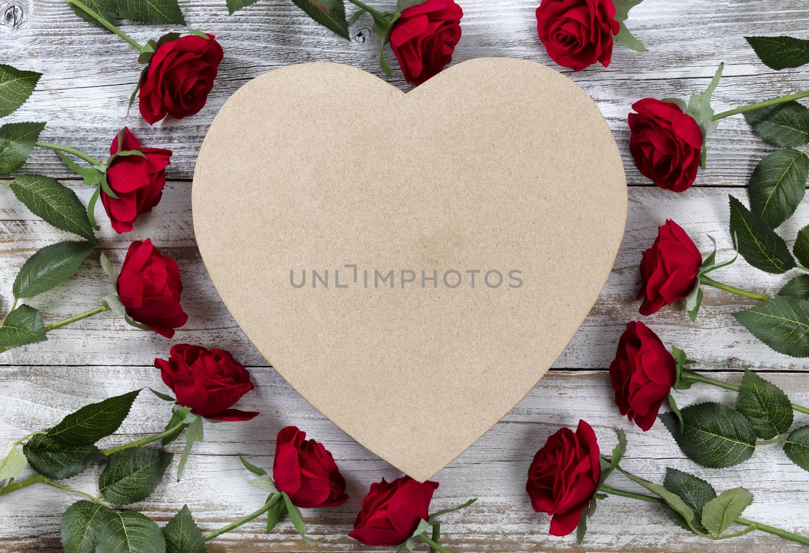 Happy Valentines Day with red roses surrounding a heart shaped gift box on white rustic wood  