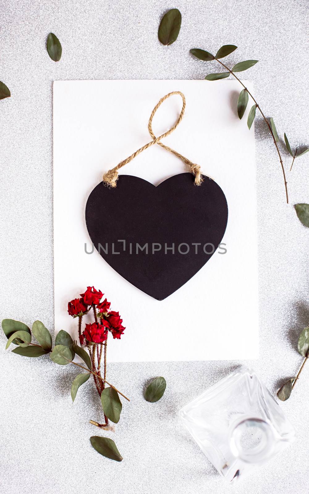 Background with copy space blank on table with black heart, eucalyptus branch, roses flowers and leafs. White paper top view, flat lay, minimal style. Moke up card. by Denys_N