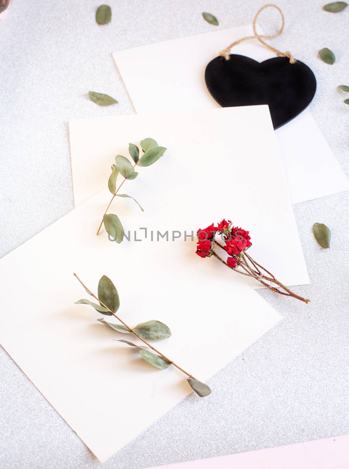 Background with copy space blank on table with black heart, eucalyptus branch, roses flowers and leafs. White paper top view, flat lay, minimal style. Moke up card. by Denys_N