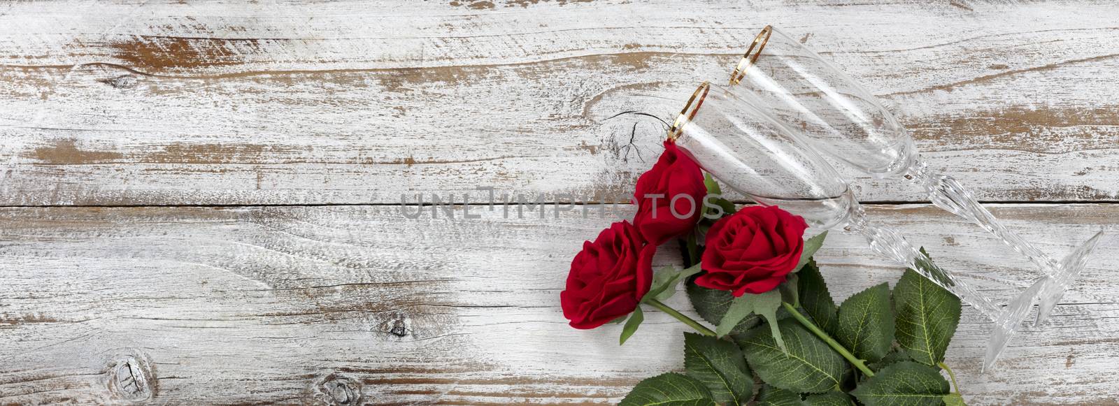 Happy Valentines Day celebration with red roses and drinking glasses on white rustic wooden background   