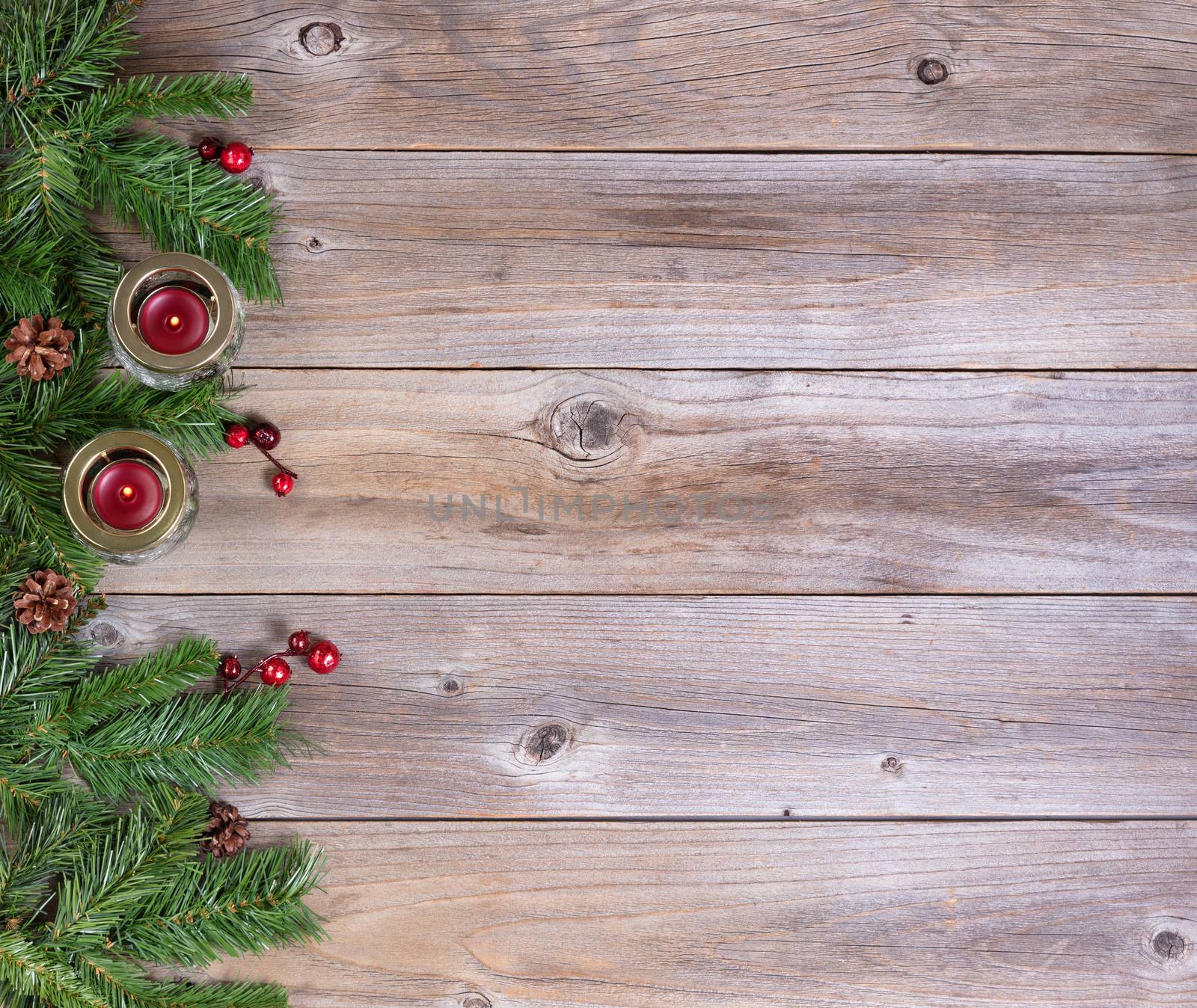 Christmas fir branches and candles on rustic wooden boards  by tab1962