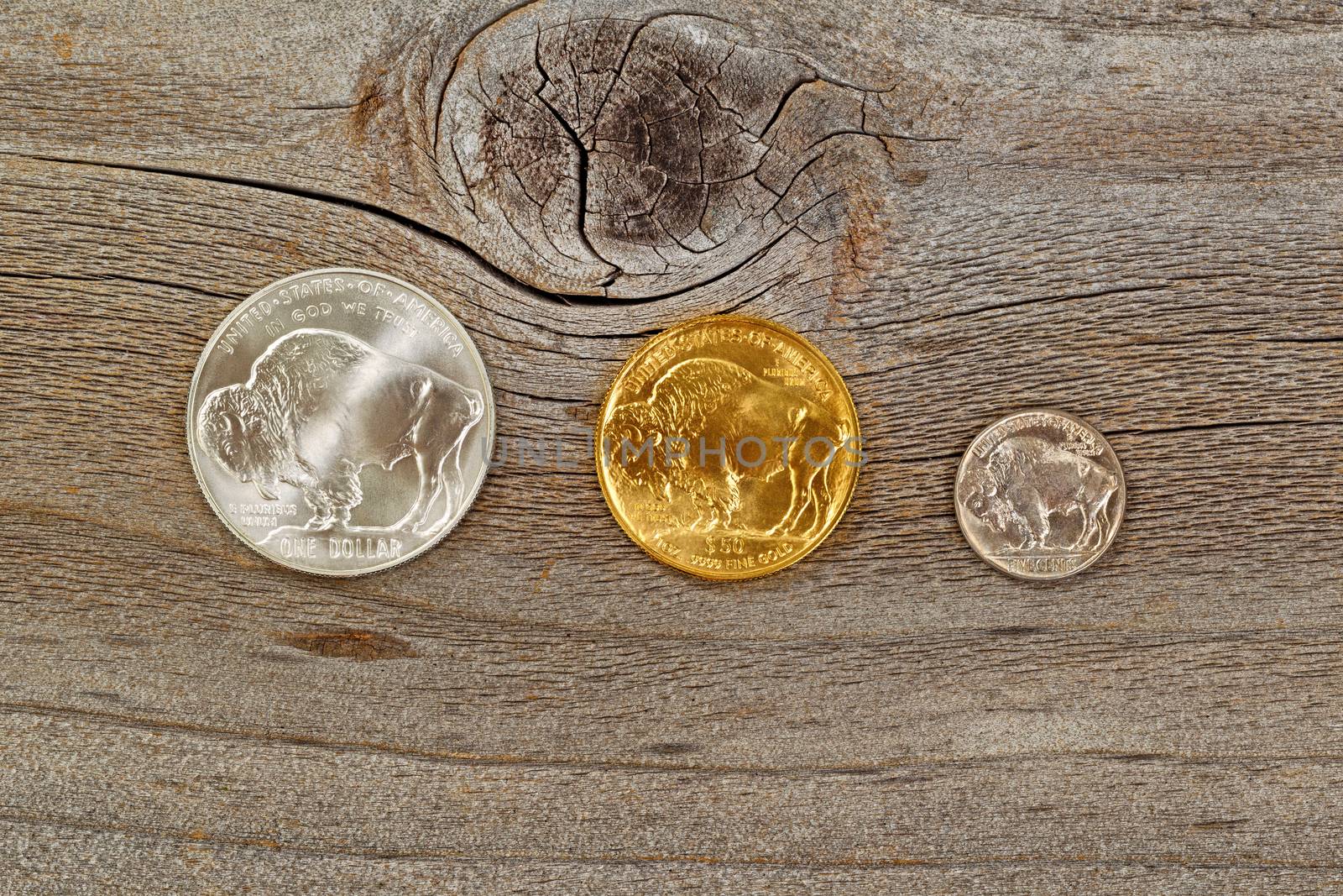 United States Mint issued reverse side of American Buffalo coins, consisting of silver, gold and nickel metals, on rustic wood. 