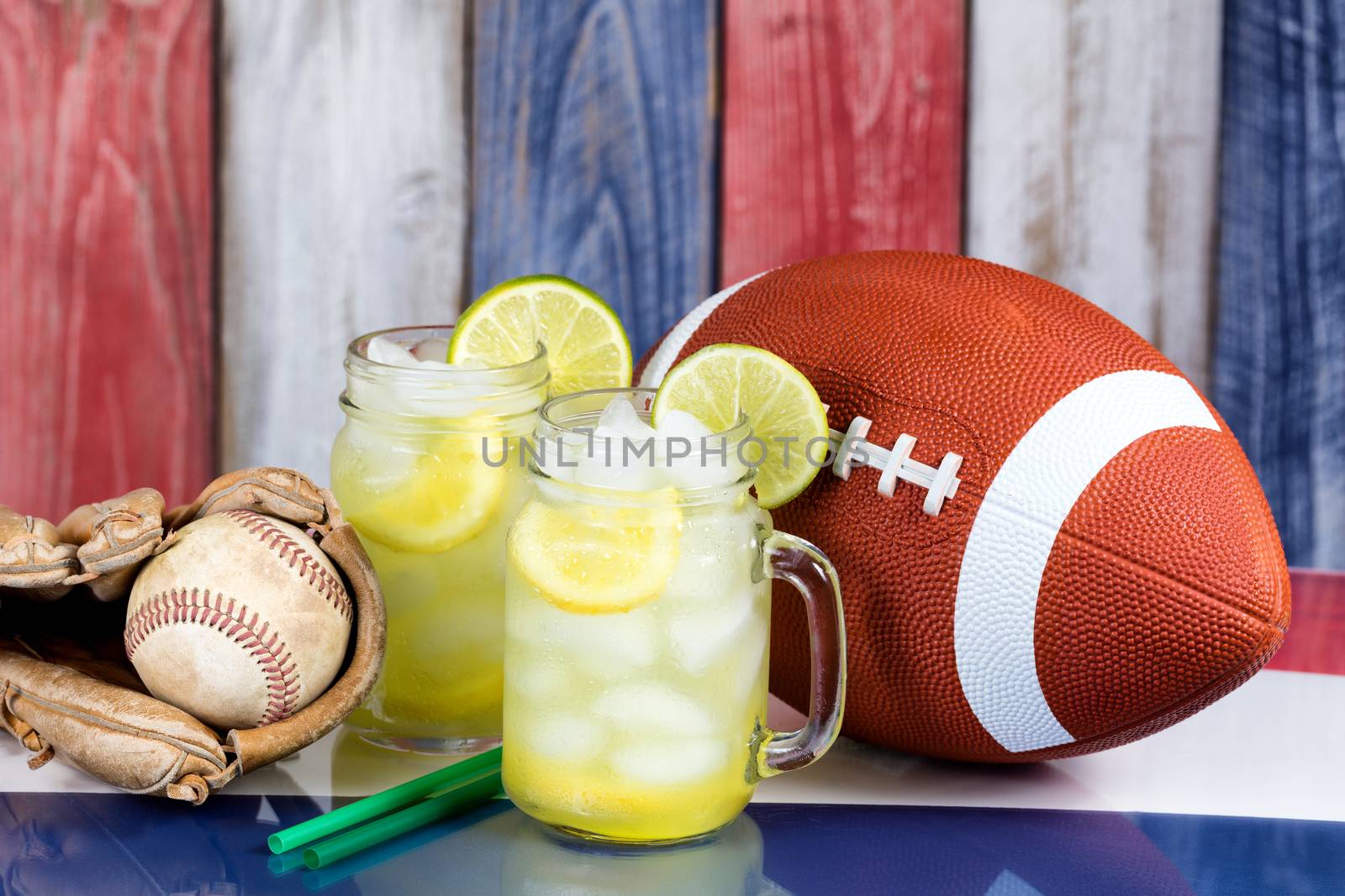 Glass jars filled with cold lemonade along with sporting objects by tab1962