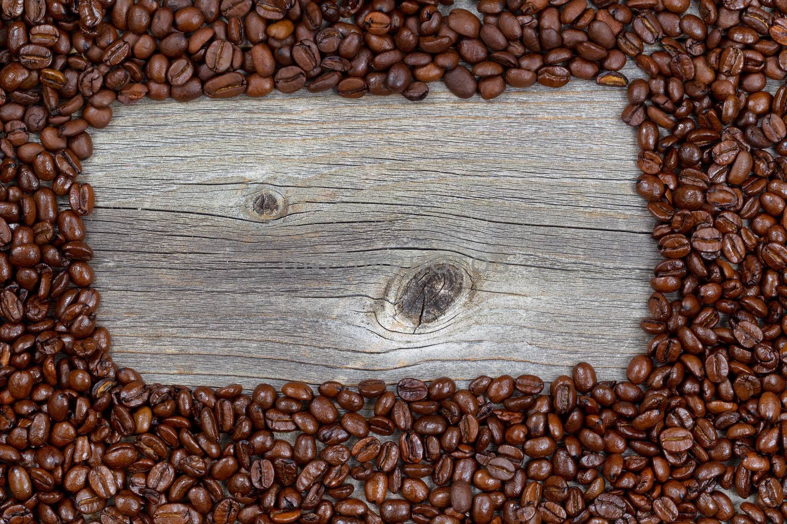 Border of freshly roasted coffee beans on aged wood  by tab1962